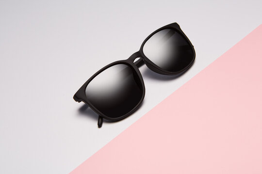 Sun glasses, folded shades lie diagonally on pink.