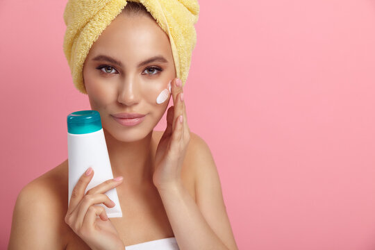 Pretty woman with blank plastic tube applies cream on skin