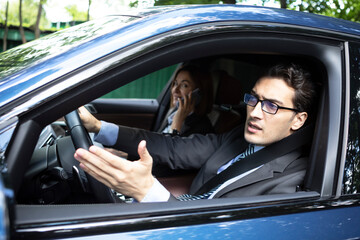 Handsome business man driving and peeps out of the window of his luxury car. Discontented man in black suit standing in traffic jam and looking out of his car and demonstrating his displeasure