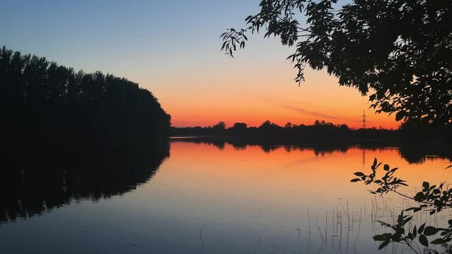 Reflection of sunlight over Chagan river surface in slow motion in Kazakhstan, Uralsk. Orange and blue light. Park or forest