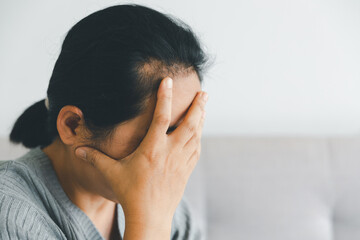 Unhappy woman touching hair, sitting on floor at home, thinking about problems, upset girl feeling lonely and sad, psychological and mental troubles, suffering from bad relationship or break up