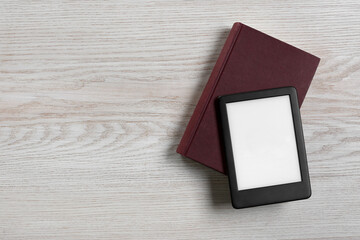Portable e-book reader and hardcover book on white wooden table, top view. Space for text