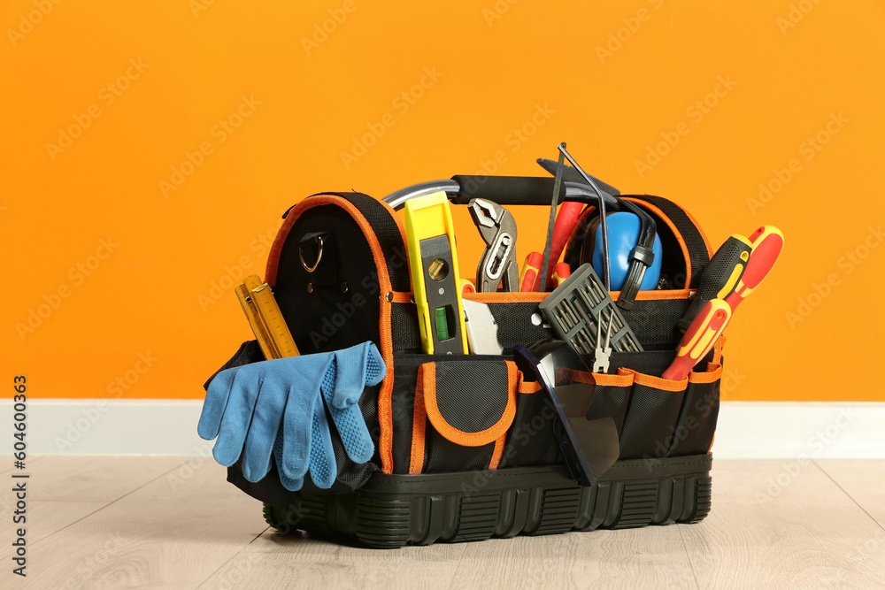 Sticker Bag with different tools for repair on floor near orange wall