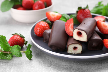 Delicious glazed curd snacks with fresh strawberries and mint on light grey table, closeup