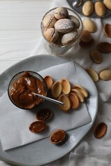 Delicious walnut shaped cookies with condensed milk on white wooden table, flat lay