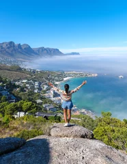 Crédence de cuisine en verre imprimé Montagne de la Table women with hands up at The Rock viewpoint in Cape Town over Campsbay, view over Camps Bay with fog over the ocean. fog coming in from the ocean at Camps Bay Cape Town South Africa
