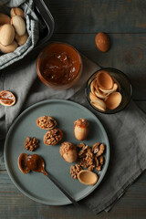 Freshly baked homemade walnut shaped cookies with nuts and boiled condensed milk on wooden table, flat lay
