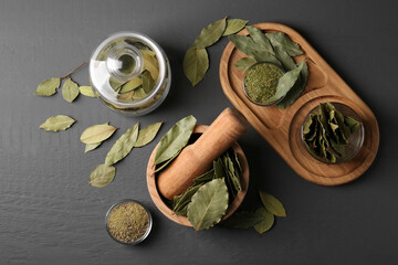 Whole and ground bay leaves on grey wooden table, flat lay