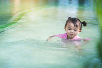 Fototapeta na wymiar Girl wearing a swim suit splashing in the swimming pool.
