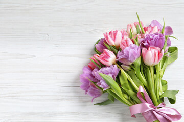 Beautiful bouquet of colorful tulip flowers on white wooden table, top view. Space for text