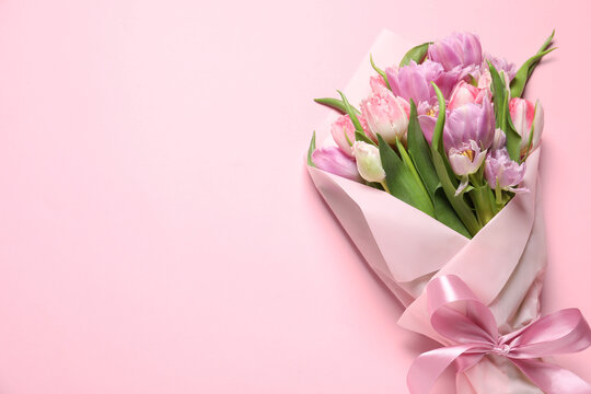 Beautiful bouquet of colorful tulip flowers on pink background, top view. Space for text