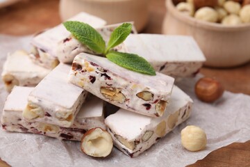 Pieces of delicious nutty nougat on white parchment paper, closeup