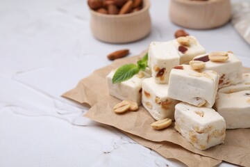 Pieces of delicious nutty nougat on parchment paper, closeup. Space for text
