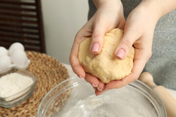 Woman holding raw dough at table, closeup