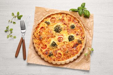 Delicious homemade vegetable quiche and cutlery on wooden table, flat lay