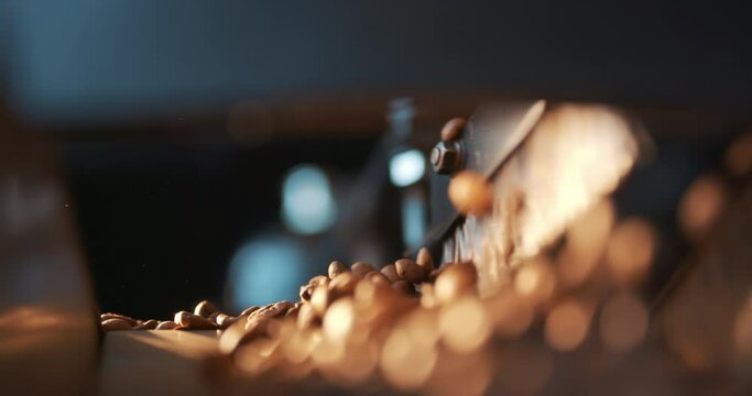 Roasted coffee beans fly and spin on a black background in slow motion. Production of fresh fried coffee beans roasting factory process. Prepared coffee beans mixing around on a cooling plate of oven.