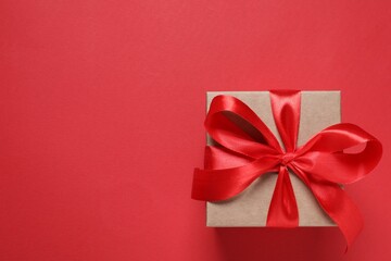 Beautiful gift box with bow on red background, top view. Space for text