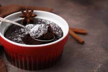 Tasty chocolate pie, anise and spoon on brown table, closeup with space for text. Microwave cake recipe