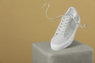 Stylish presentation of trendy sneaker on beige background. Space for text