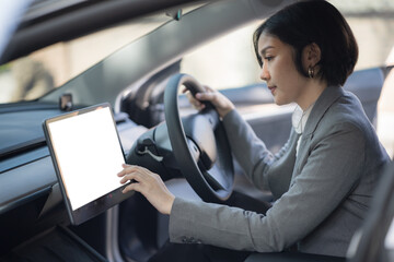 An Asian woman driving and using a touch screen GPS panel for navigation in a car.