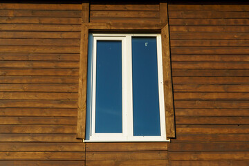 Obraz na płótnie Canvas The exterior of a new modern wooden house and double-glazed windows in wooden walls. Design and architecture of private houses. Repair and maintenance of double-glazed windows.