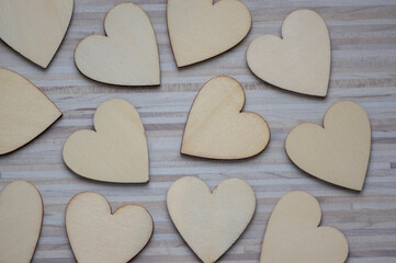 Obraz premium Love Valentines day background, group of light wooden hearts spread on gray striped table, flat lay