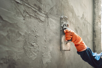 Naklejka na ściany i meble hand of worker plastering cement at wall for building house
