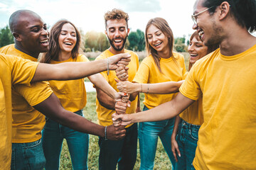 Fototapeta Multiracial happy young people stacking hands outside - University students hugging in college campus - Youth community concept with guys and girls standing together supporting each other obraz