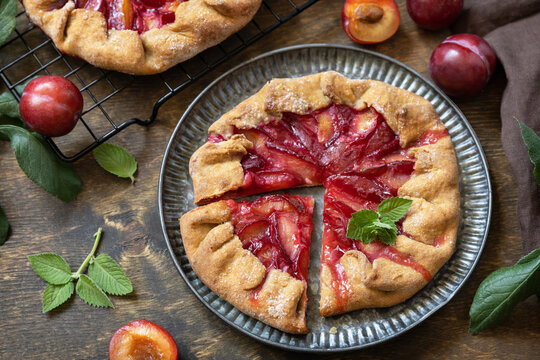 Vegan vegetarian dessert, plums galette with almonds. Healthy homemade wholegrain fruit pie, sweet crostata on a rustic table.
