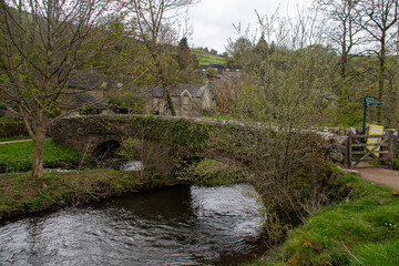Traditional medieval stone bridge crossing the River Dove in Peak District village Milldale, UK