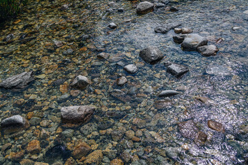 Scenic summer landscape - mountain river in a forest - crystal pure water, rocks and sunlight reflecting on the water surface.