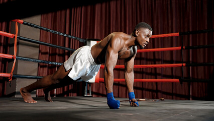 Naklejka premium African boxers are strong and muscular. Warming up on the boxing ring, wearing sports clothes, doing push-up exercises. Strengthen your body before boxing in the boxing ring in the gym.