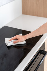 woman housewife wipe electrical cooker top with towel, closeup