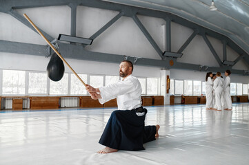 Confident and strong mature aikido master training with bokken Japanese sword