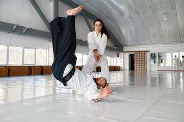 Talented female student throwing aikido teacher on floor