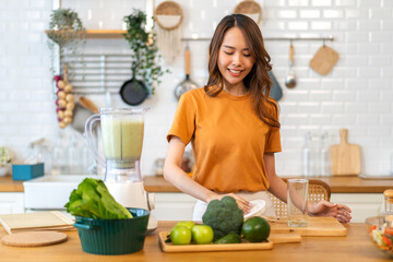 Portrait of beauty healthy asian woman making green vegetables detox cleanse and green fruit smoothie with blender.young girl drinking glass of green fruit smoothie in kitchen.Diet concept.healthy 