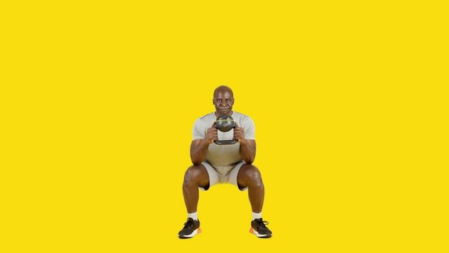 Sportive african man doing globet squat with kettlebell