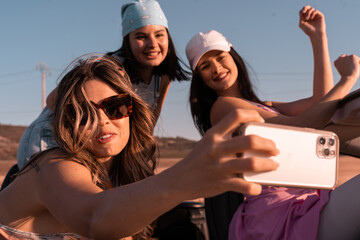 During the summer trip the young girl takes a selfie while her friends are smiling. They are...