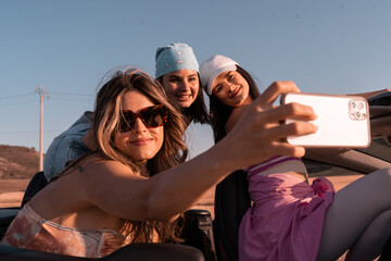 During the summer trip, the three young friends take a selfie while smiling. They are traveling in...