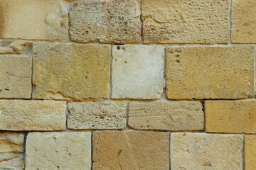 Background, texture wall lined with natural porous sandstone stone in warm color