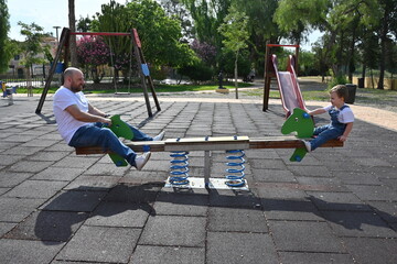 father and son having fun on the swing in the playground
