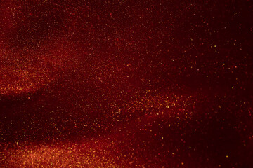 Glittering flows of gold particles in red fluid.