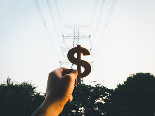 Businessman's hand holding a symbol Dollar with electric pole background, concept of electricity...