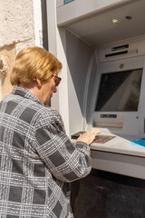 Senior woman using an ATM .