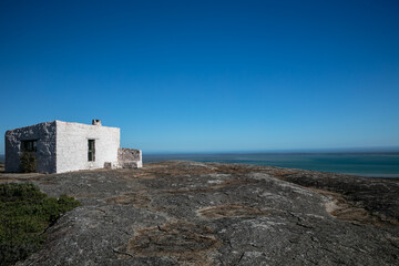Fototapeta na wymiar View of Seeberg cottage on a granite boulder overlooking the turquoise water of Langebaan lagoon in the West Coast National Park, South Africa