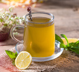 A glass of mint lemon tea. Healthy herbal teas. Lemon with mints on wooden table