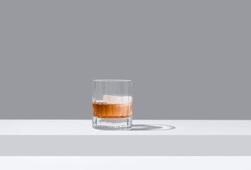 Vaso de whisky con hielo sobre un fondo gris