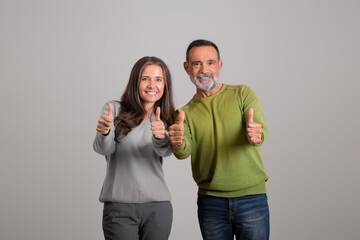 Fototapeta premium Positive caucasian aged family show thumbs up, approving service, isolated on gray background