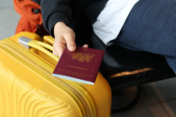 Dutch citizen Hand holding Netherlands Passport with yellow Suitcase waiting at terminal airport.