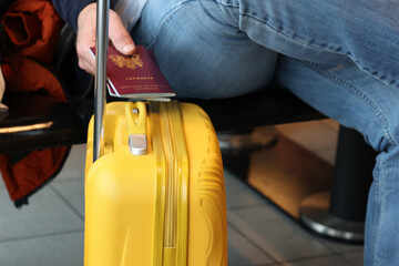 Dutch citizen Hand holding Netherlands Passport with yellow Suitcase waiting at terminal airport.